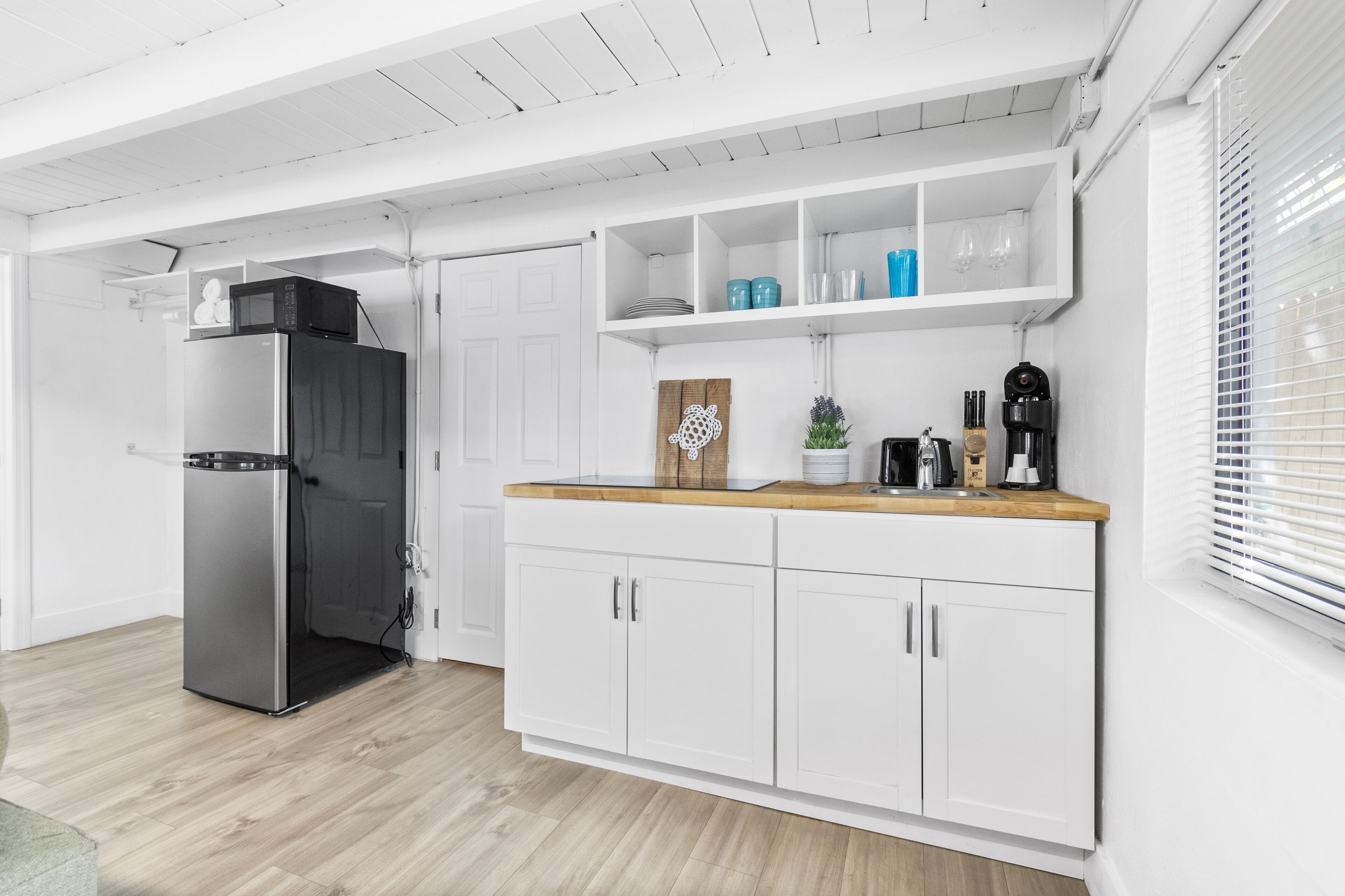 Eine moderne Küche mit weißen Schränken, einem Edelstahlkühlschrank und einer Holz Arbeitsplatte.