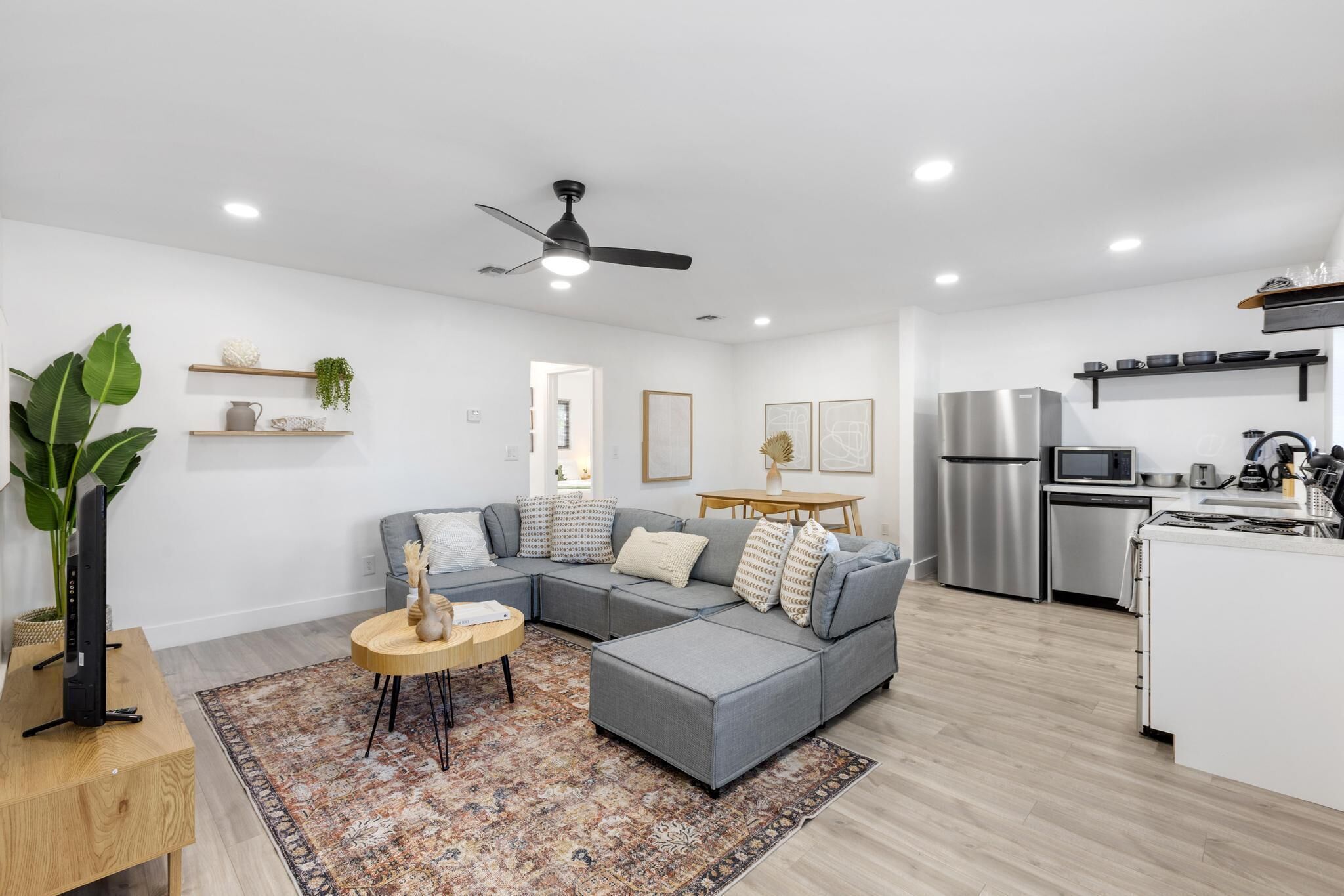 Uma sala de estar moderna com um sofá modular cinza, uma mesa de centro redonda e uma planta grande.