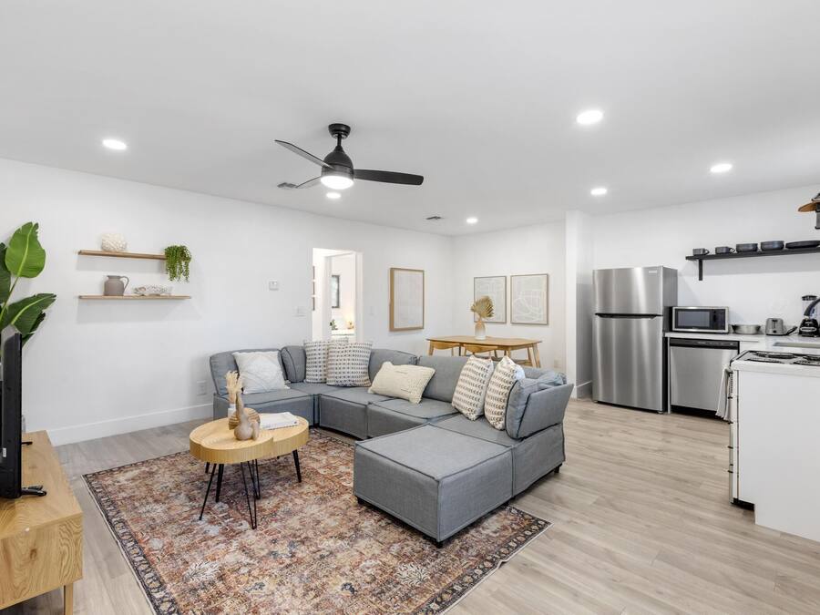 A modern living room with a grey sectional sofa, a round coffee table, and a large plant.
