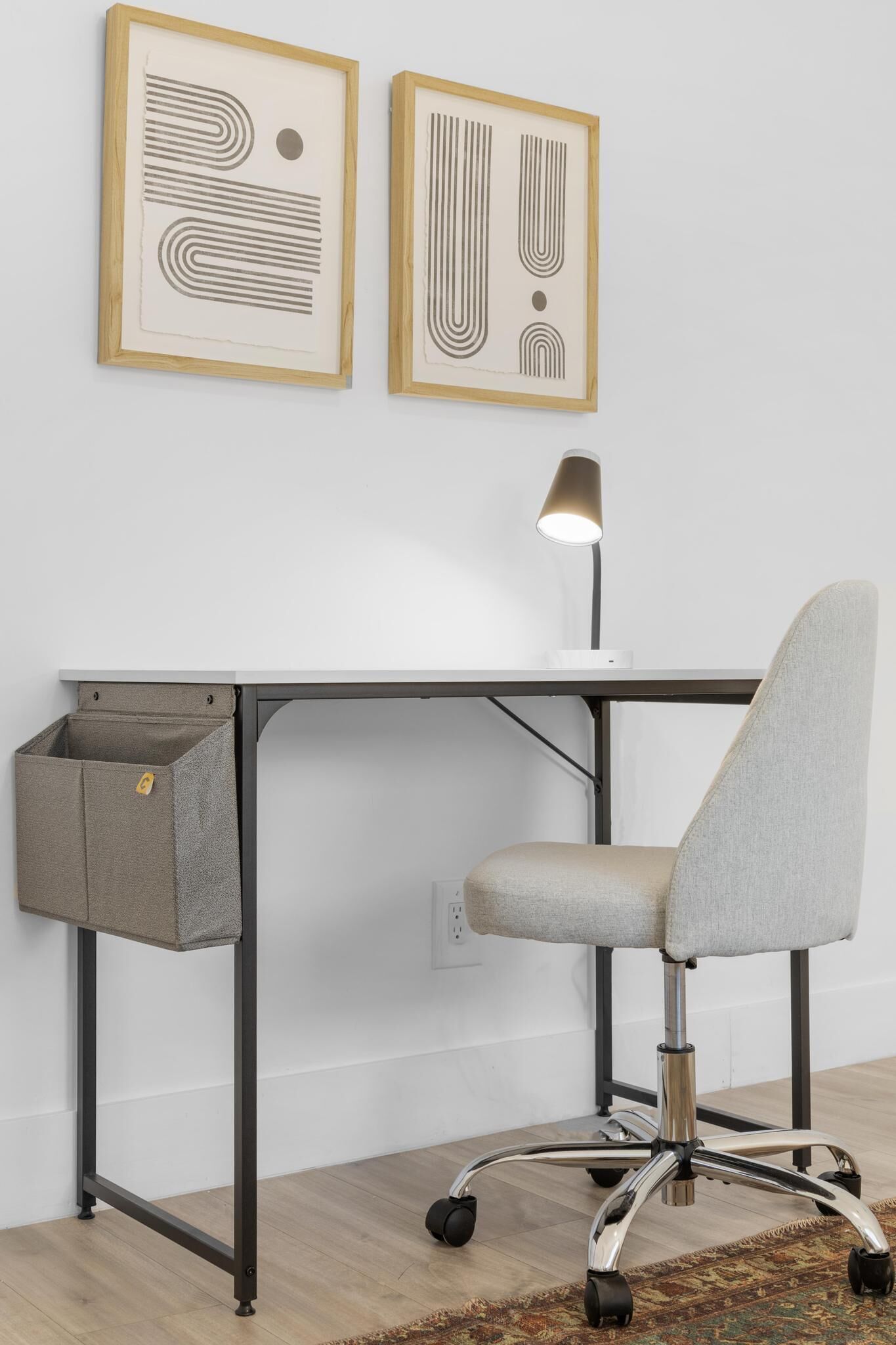 Un bureau moderne avec une chaise de bureau grise, une lampe et une corbeille à papier.