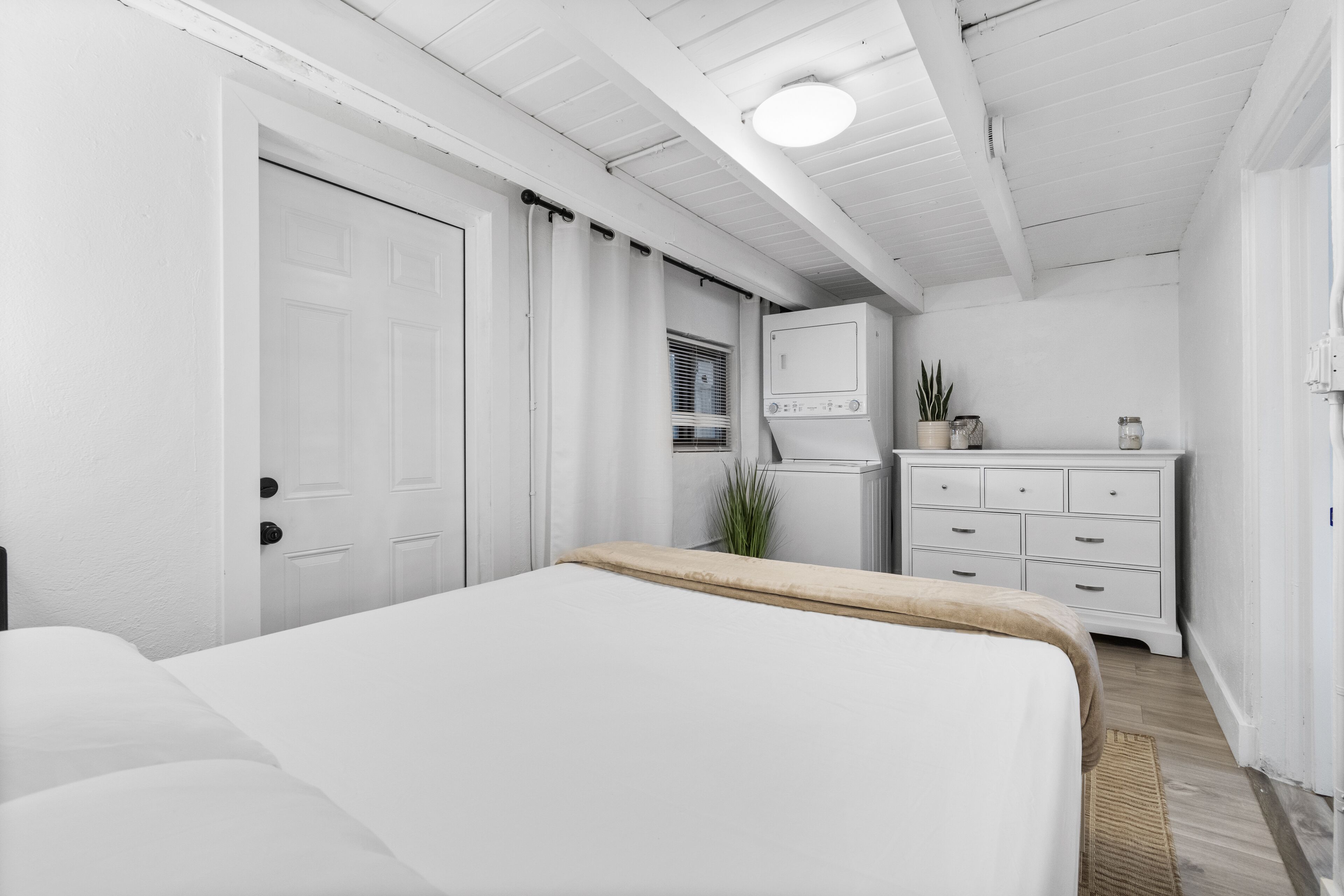 Un dormitorio con cama, cómoda, espejo y ventana con persianas.