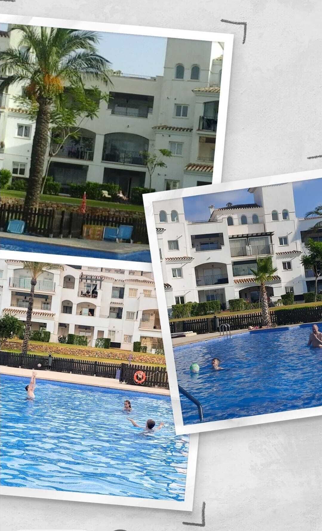 A hotel with a swimming pool, palm trees, and a white building with balconies.