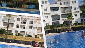 Um hotel com piscina, palmeiras e um edifício branco com varandas.