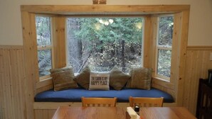 A cabin with a built-in bench by a window, a table, and a candle.