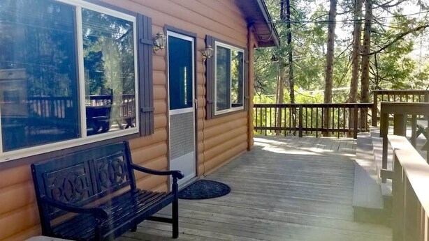 A wooden cabin with a covered porch, a bench, and a door with a window.