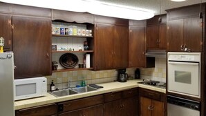 A kitchen with wooden cabinets, a microwave, a sink, a stove, and a refrigerator.
