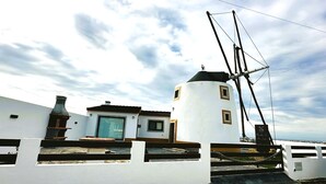 En kystbygning med skorsten, et lille vindue og en balkon med gelænder.