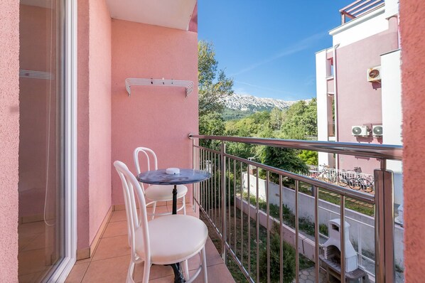 A balcony with a table and chairs, a hanging laundry rack, and a view of a mountain and greenery. - With air conditioning, WiFi, balcony only 350 metres to the beach (Baska)