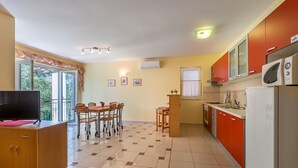 A modern kitchen with a dining area, a TV, and a balcony with curtains. - With air conditioning, WiFi, balcony only 350 metres to the beach (Baska)