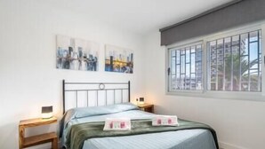 Une chambre à coucher avec un lit, deux tables de chevet et une fenêtre avec des stores.