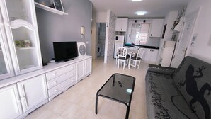 Ein Wohnzimmer mit einer Couch, einem Couchtisch, einem Fernseher und einem Essbereich mit Stühlen und Tisch.