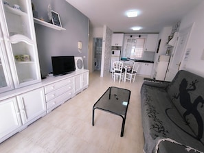Relax in this stylish living room with a flat-screen TV, glass coffee table, and comfortable sofa.