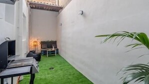 A small, enclosed outdoor area with a green artificial turf, a sofa, a small table, and a lamp. - Branmi House Big Ravine (Santa Cruz de Tenerife)
