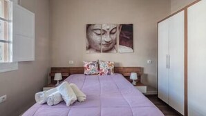 A bedroom with a bed, pillows, a nightstand, a wall-mounted painting, and a wardrobe. - Branmi House Big Ravine (Santa Cruz de Tenerife)