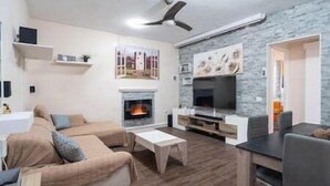 A living room with a fireplace, a television, and a ceiling fan. - Branmi House Big Ravine (Santa Cruz de Tenerife)