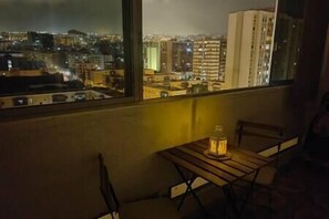 A balcony with a table and chairs, overlooking a cityscape at night. - Chito House Santa Cruz (Santa Cruz de Tenerife)