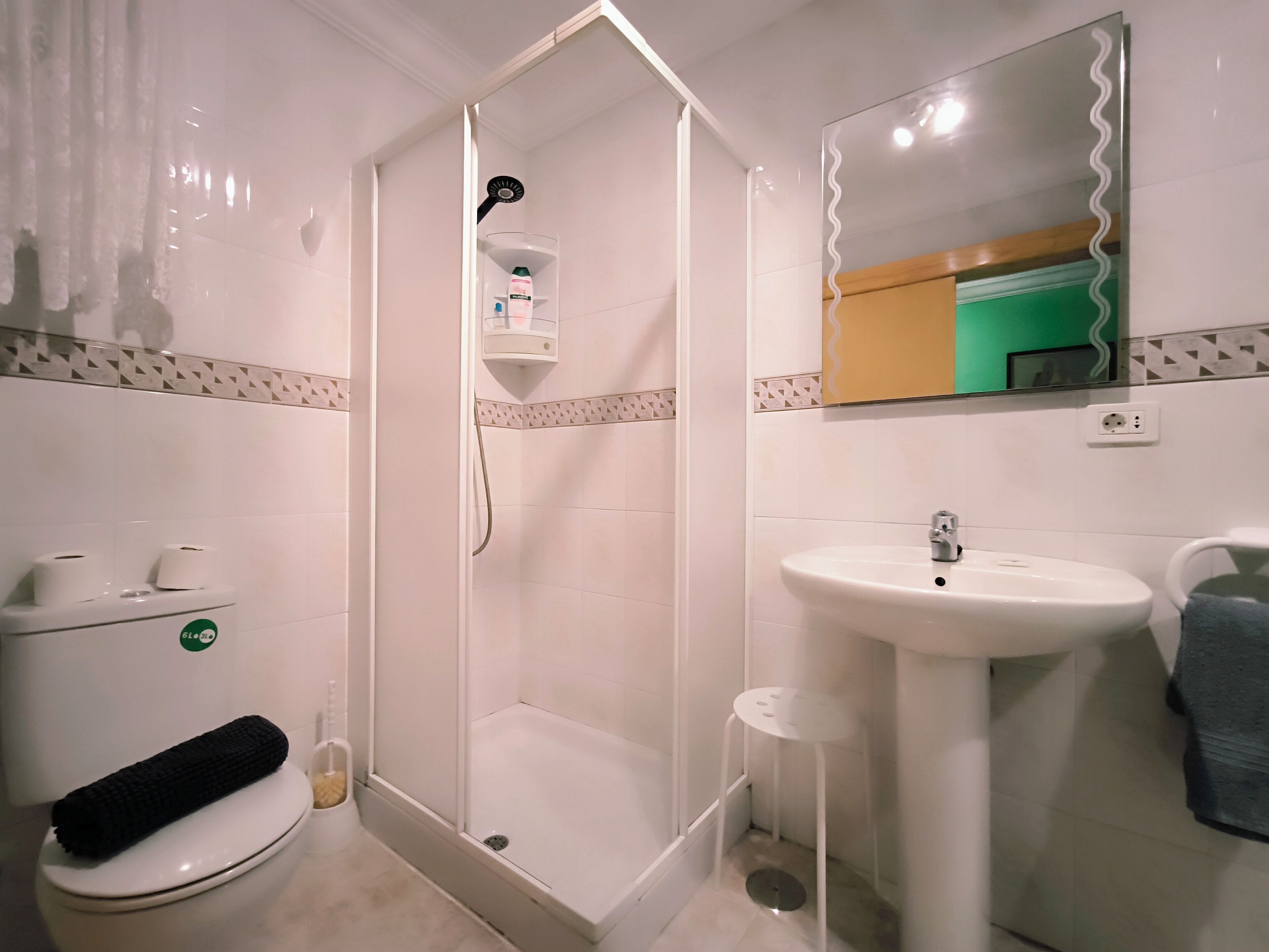 Un baño con inodoro, lavamanos, ducha y espejo.