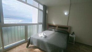 A bedroom with a large window, a bed, and a nightstand. - Sunset with views of Teide (Mesa del Mar)