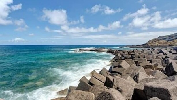 A rocky coastline with waves crashing against large boulders under a clear sky. - Sunset with views of Teide (Mesa del Mar)