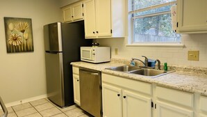 A kitchen with white cabinets, a stainless steel refrigerator, a microwave, and a double sink. - Warm welcoming stay (Mandeville)
