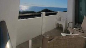 A balcony with a view of the sea, white walls, and a chair. - Condo on the Caribbean (Isla Mujeres)