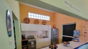 A compact kitchen with white cabinets, a gas stove, a refrigerator, and a water dispenser. - Condo on the Caribbean (Isla Mujeres)