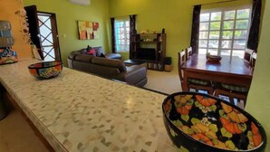 A spacious living area with a sofa, a dining table, and a TV. - Condo on the Caribbean (Isla Mujeres)