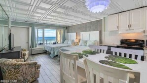 Een ruime slaapkamer met een groot bed, een eethoek met een tafel en stoelen, en uitzicht op de oceaan door grote ramen.