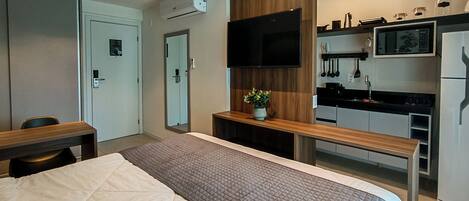 Una camera d'albergo con un letto, una scrivania, angolo cottura e televisione.