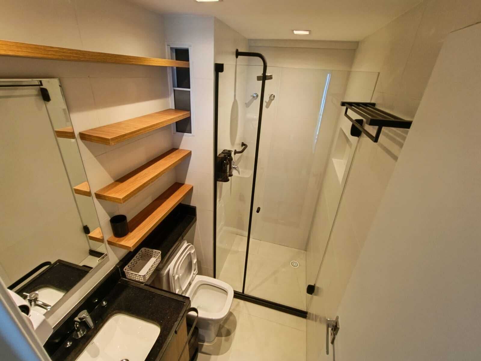 A modern bathroom with a glass shower enclosure, a sink, a toilet, and wooden shelves.