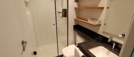 A modern bathroom with a glass shower enclosure, a white sink, and wooden shelves above the counter.