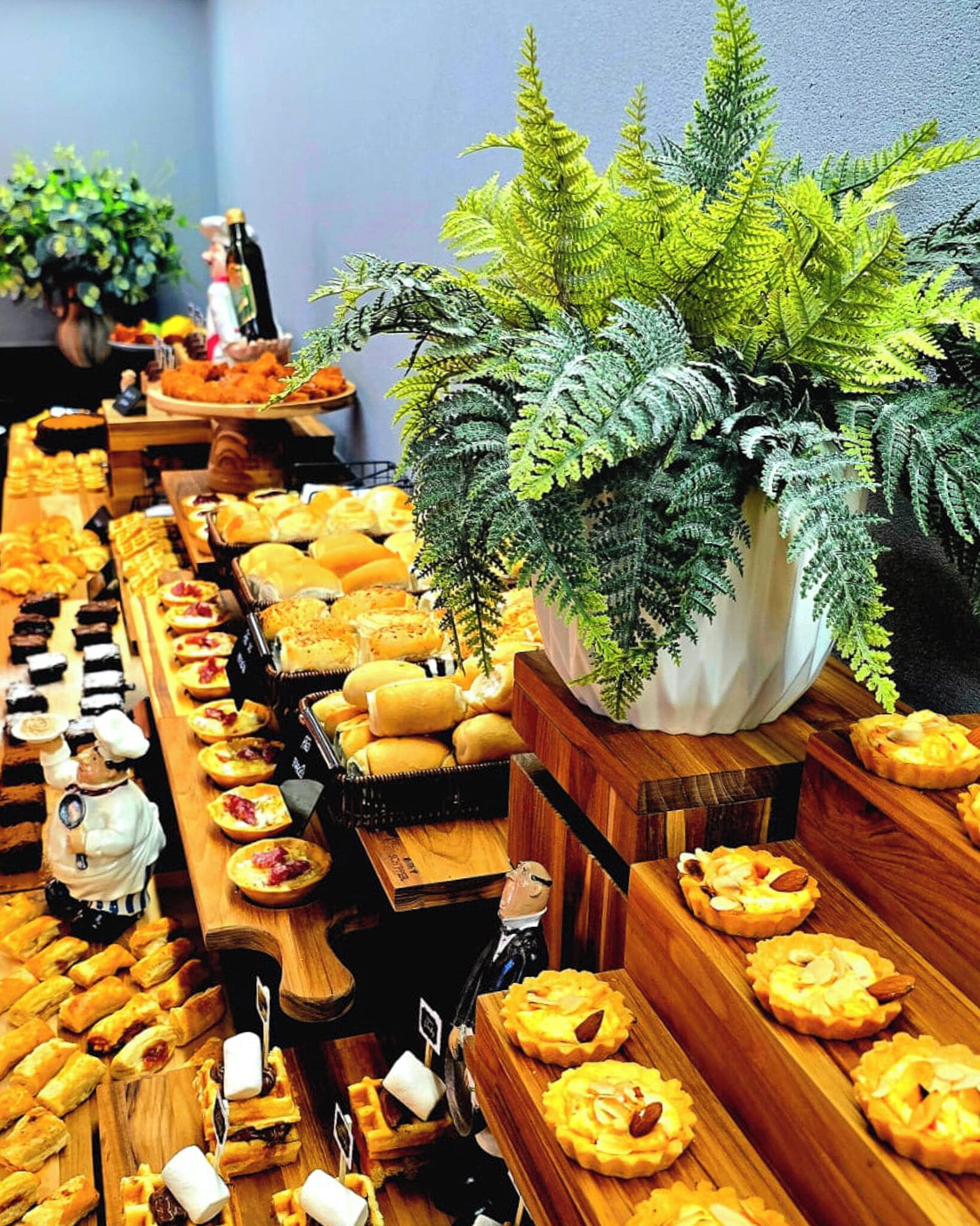 A buffet with various food items, including pastries and sandwiches, arranged on wooden tables.