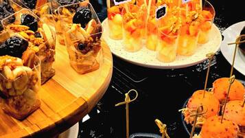 Buffet com diversos alimentos, incluindo frutas, sobremesas e petiscos.
