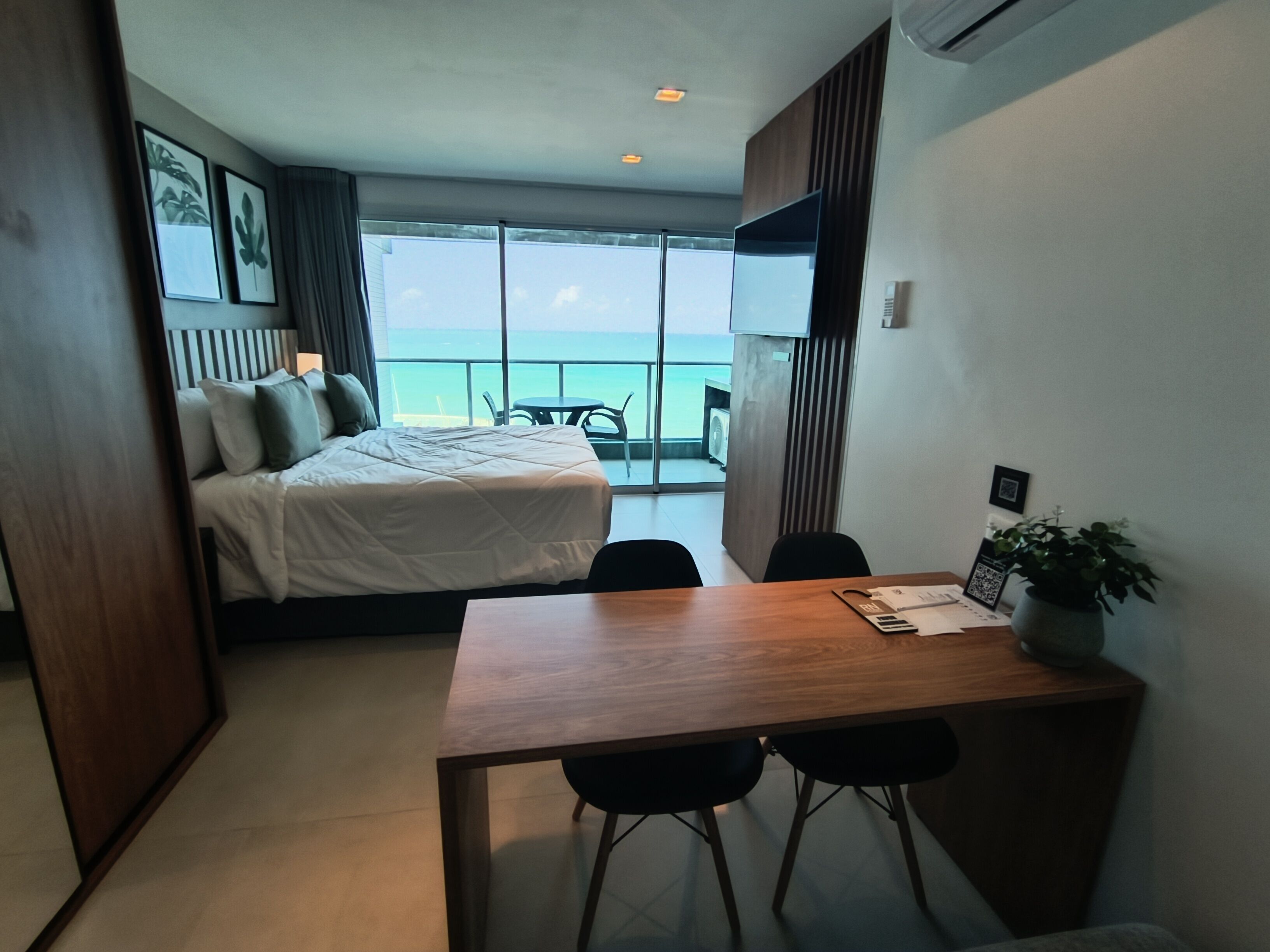 Une chambre d’hôtel avec un lit, un bureau et une vue sur la mer.