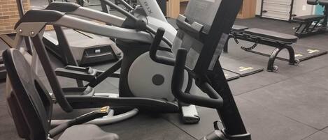 Et fitnesscenter med forskellig træningsudstyr, herunder løbebånd og styrkemaskiner, i moderne belysning.