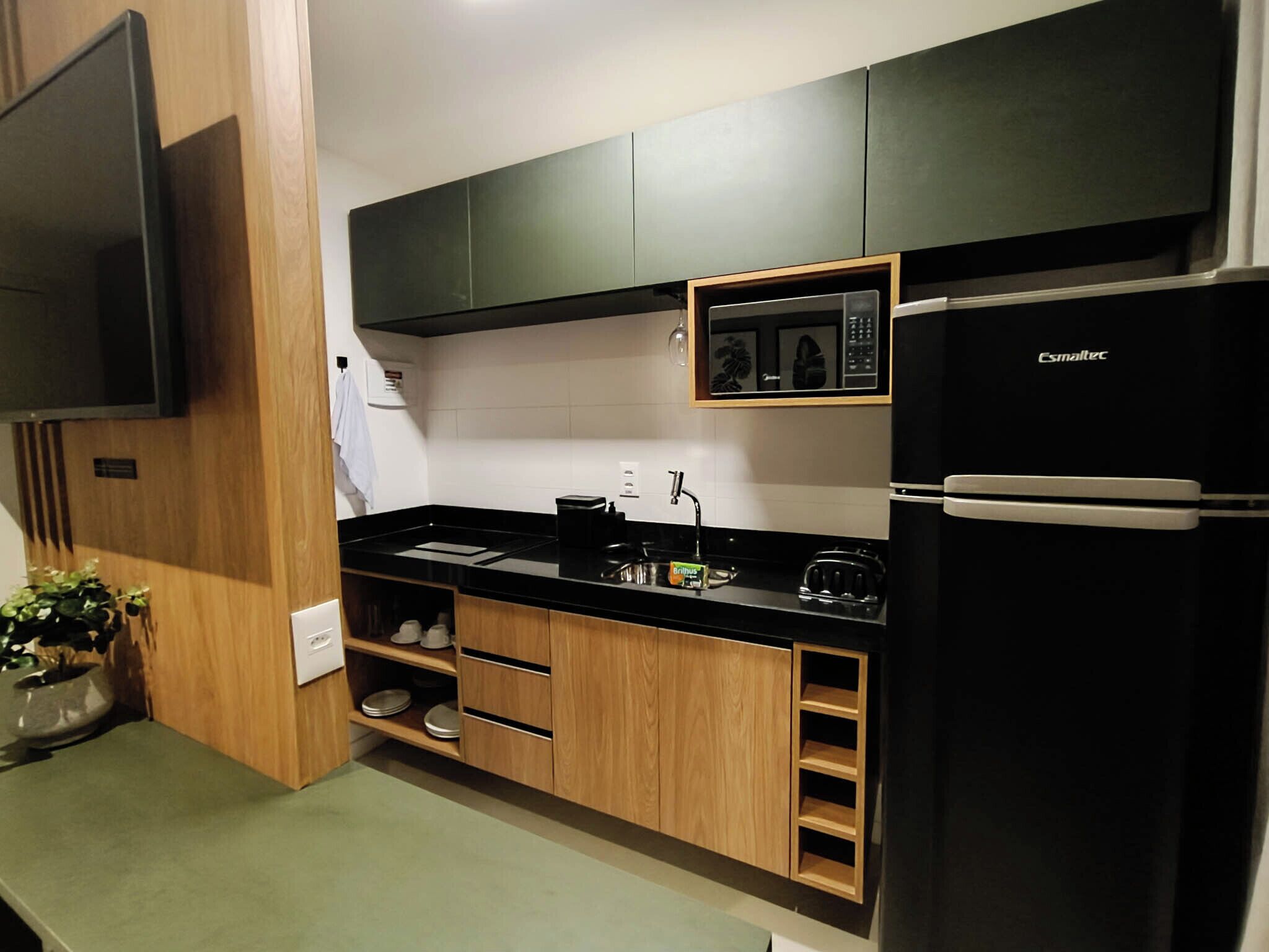 A modern kitchen with black appliances, wooden cabinets, and a black countertop.