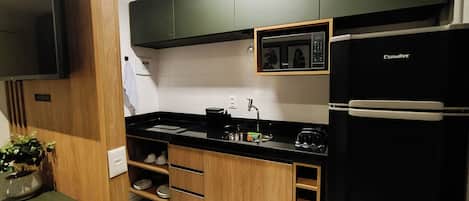 A modern kitchen with black appliances, wooden cabinets, and a black countertop.