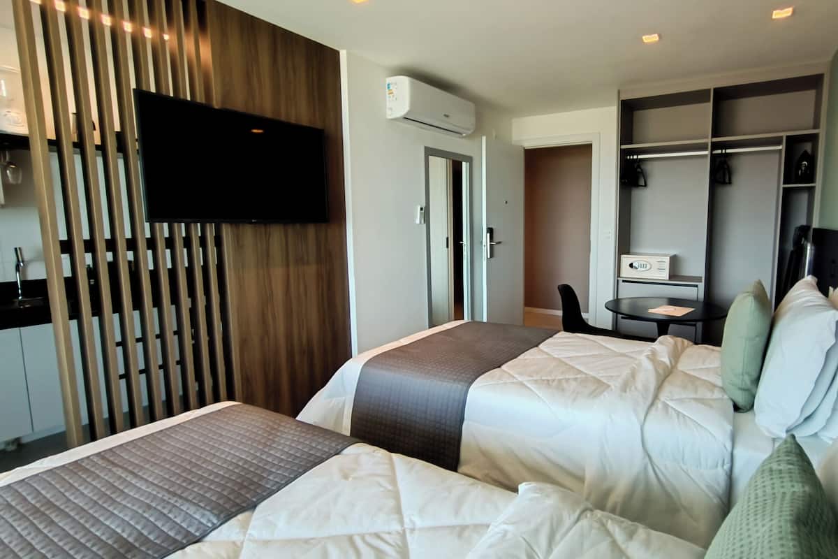 A hotel room with two beds, a TV, a desk, and a wardrobe.