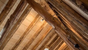 A cozy attic bedroom with wooden beams and a sloped ceiling, featuring two beds with white linens.
