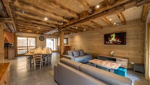 A cozy log cabin interior with a dining area, sofa, and a fireplace.