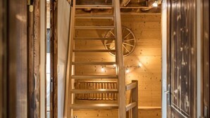 A wooden staircase with a handrail, a wooden wall with a circular window, and a door on the right.