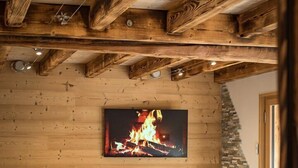 A cozy living room with a fireplace, wooden beams, and modern furniture.