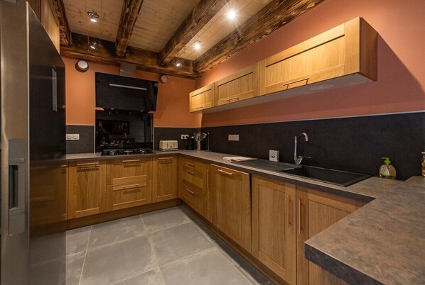 A kitchen with wooden cabinets, a black countertop, and a tiled floor.