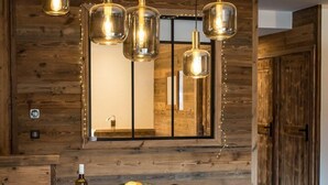 A dining area with a wooden wall, a large mirror, and pendant lights. - Top of the range flat with a large terrace in the heart of the village - sleeps 6 (ST SORLIN D ARVES)