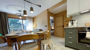 Una cocina moderna con armarios de madera, horno empotrado y comedor con mesa dispuesta para cuatro.