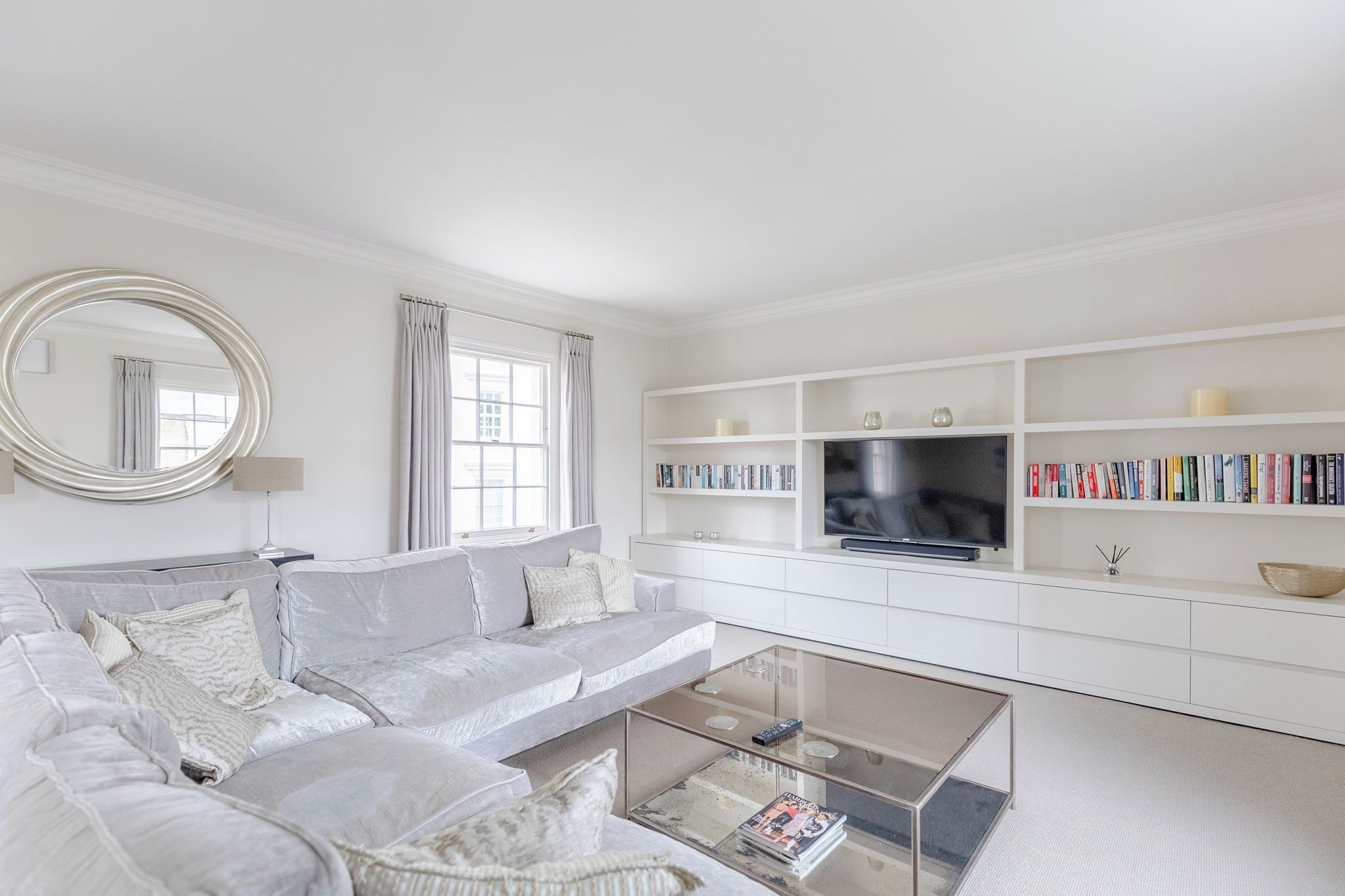 Una sala de estar moderna con sofá, una mesa de centro, televisor y estantería.