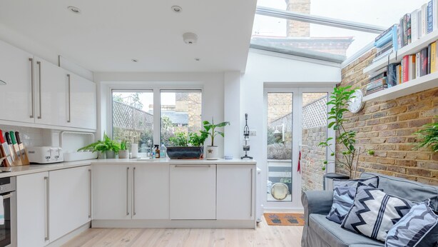A modern kitchen with white cabinetry, a central island, and a built-in bookshelf. - Beautifully Designed 2BD House - by Queen's Park! (London)