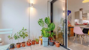 A modern kitchen with a dining area, a glass door leading to a balcony with potted plants. - Bright 1 BDR Flat Balcony Heart of Brixton (Brixton)