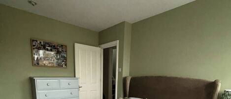 Un dormitorio con cama, cómoda y puerta que da a otra habitación.