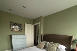 A bedroom with a bed, dresser, and a door leading to another room. - Resplendent Riverside Residence | 3 Bed | Fulham (London)